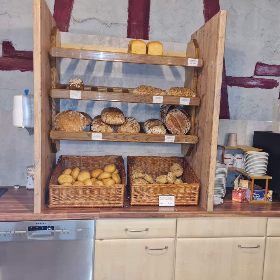Brotauslage aus Holz mit verschiedenen Brotsorten und Brötchen.