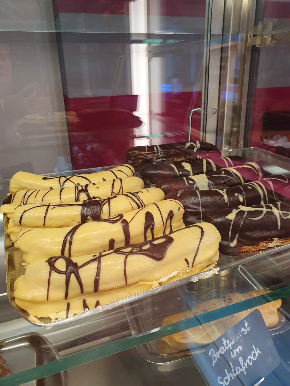Vitrine mit gelben und schokoladenbraunen Eclairs.