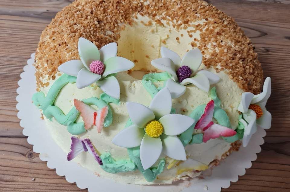 Kuchen verziert mit weißen Blüten, Schmetterlingen und Nussstreuseln.