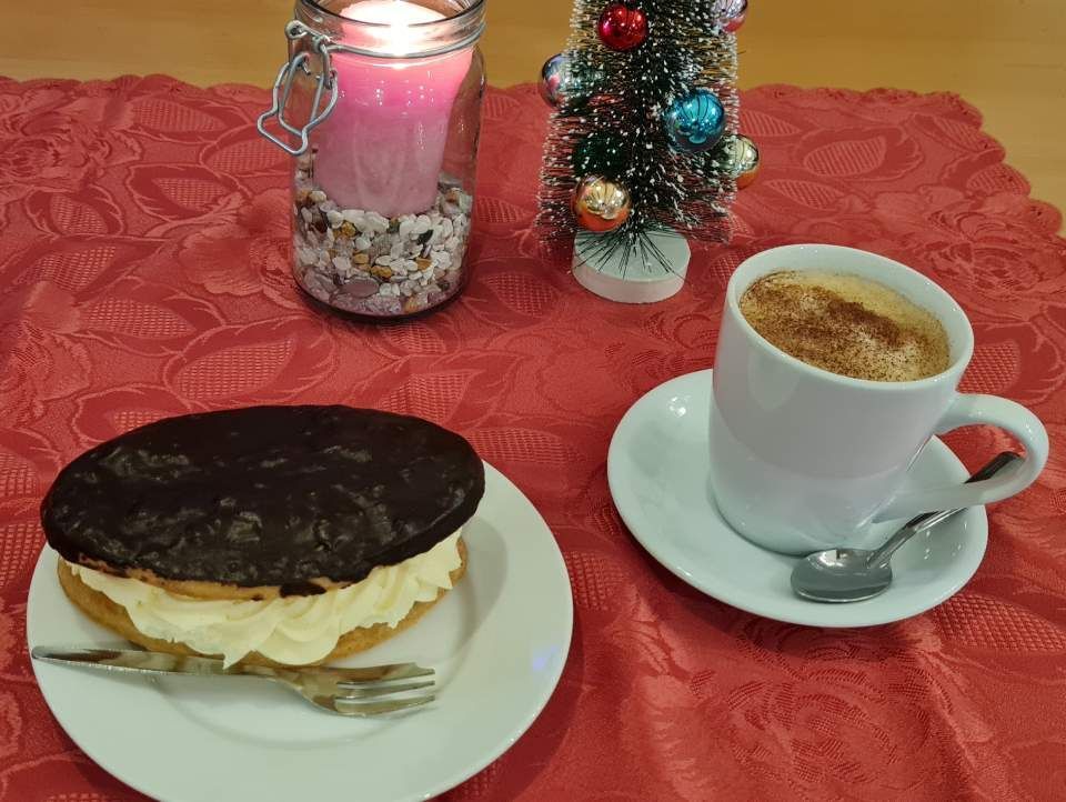 Softeis in einem dekorierten Becher auf einem Holztisch im Freien.