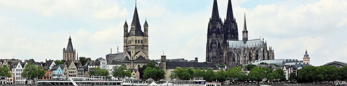 Eine Skyline einer Stadt mit einer großen Kathedrale im Vordergrund und einem Fluss im Hintergrund.