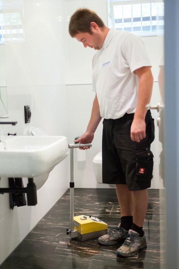 Ein Mann steht in einem Badezimmer neben einem Waschbecken und einer Toilette.