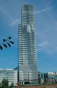 Ein hohes Gebäude mit vielen Fenstern und einem blauen Himmel im Hintergrund.