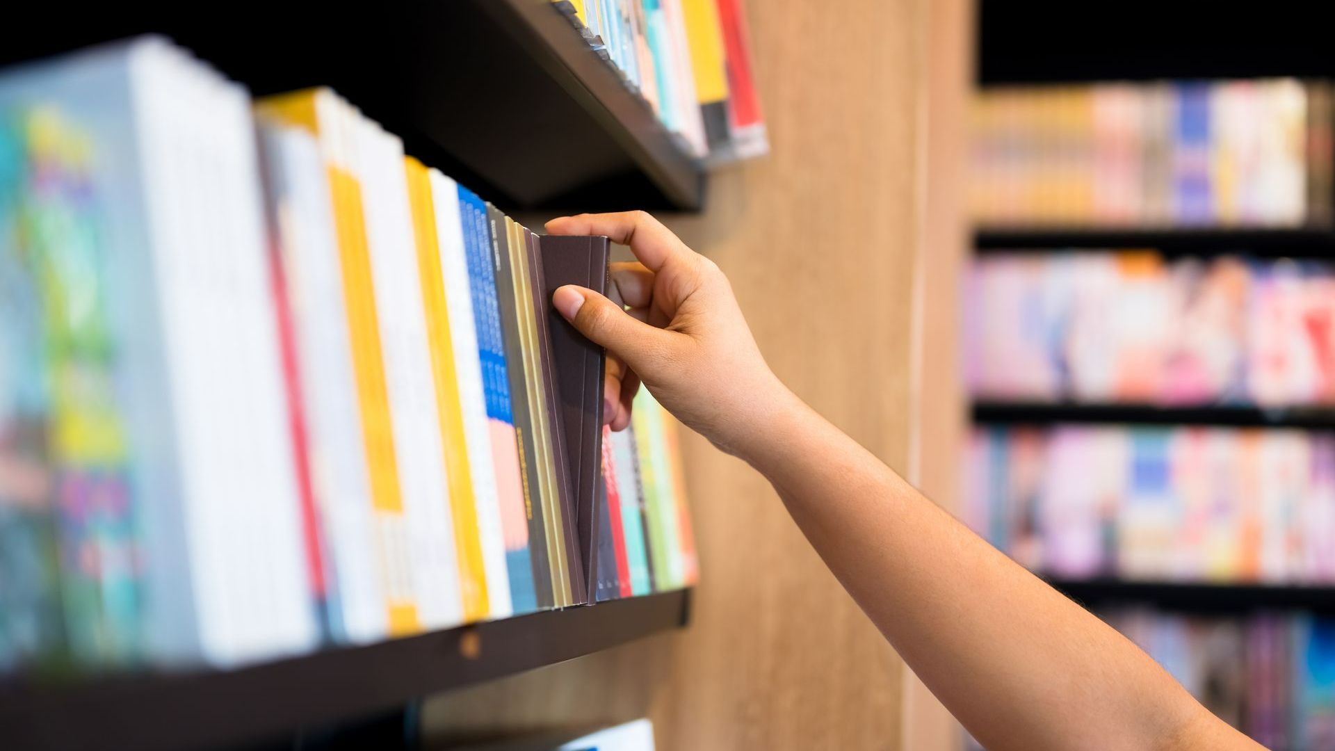 Une personne prenant un livre sur une bibliothèque