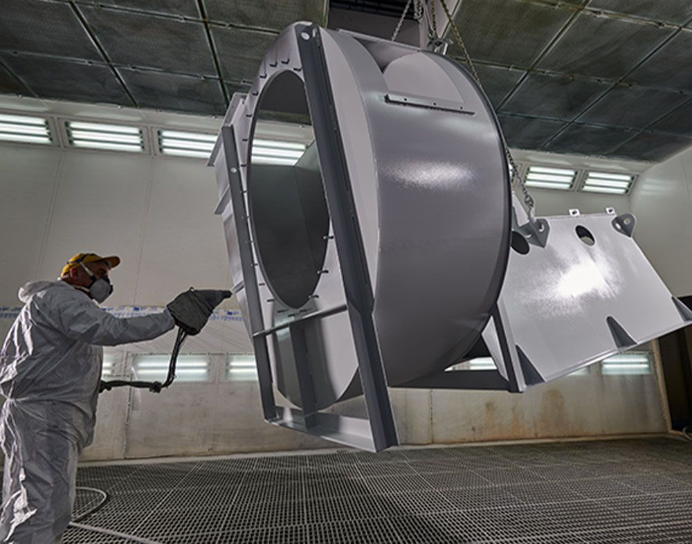 Un technicien qui applique un traitement sur le caisson d'un ventilateur