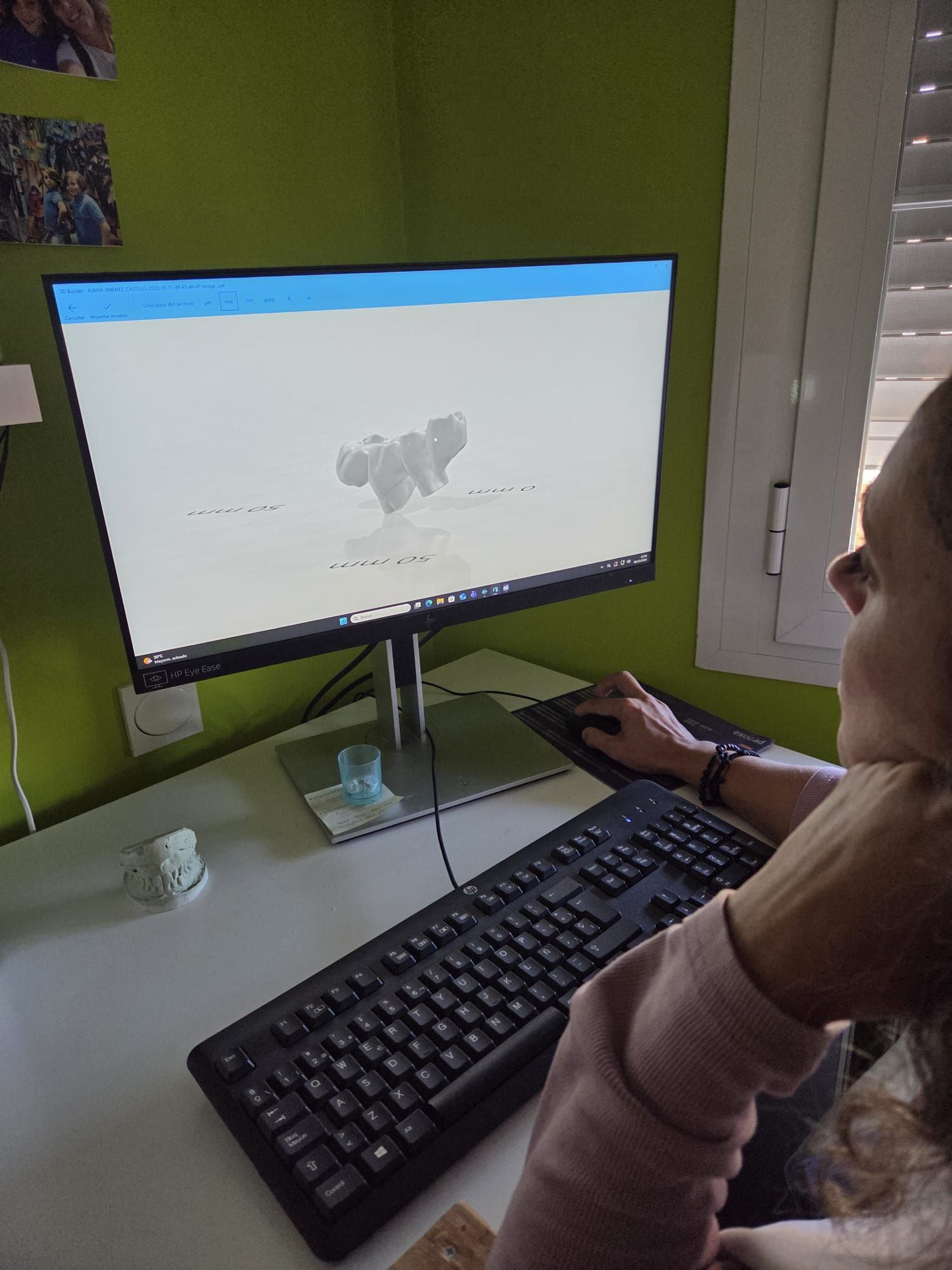 Persona usando un ordenador de sobremesa con teclado y ratón en una habitación luminosa.