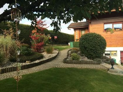 Une maison en bois est entourée d'un jardin verdoyant