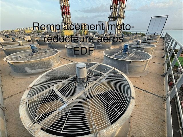 Ventilateurs et conduits de climatisation sur le toit d'un site utilitaire, avec des grues en arrière-plan.