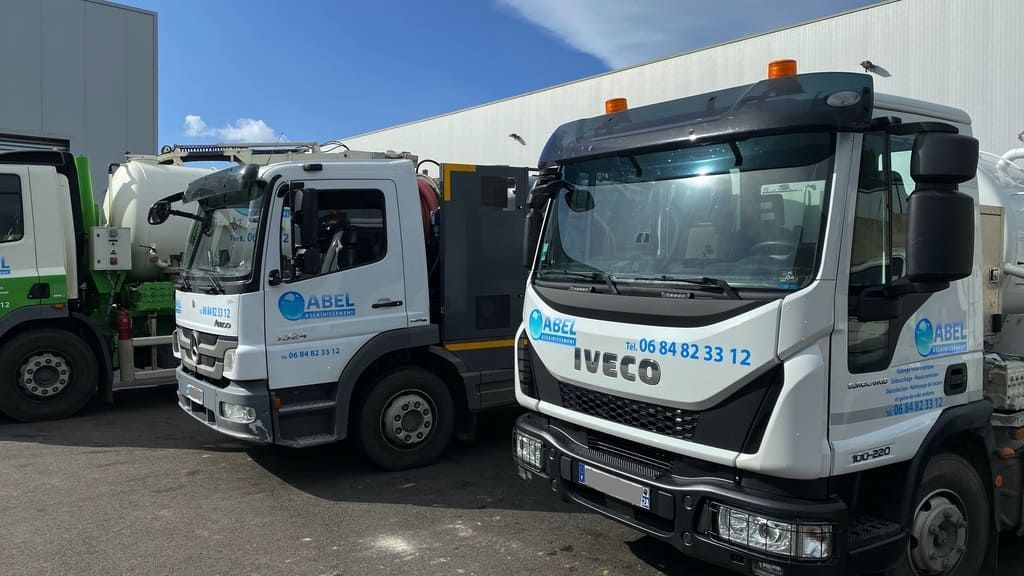 Trois camions utilitaires Iveco blancs garés côte à côte sur un terrain ensoleillé