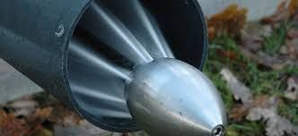 Gros plan sur un cône de nez de fusée argenté fixé à un corps cylindrique sombre en extérieur