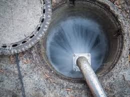 Tuyau métallique déversant de l'eau dans l'ouverture d'un réservoir circulaire en béton