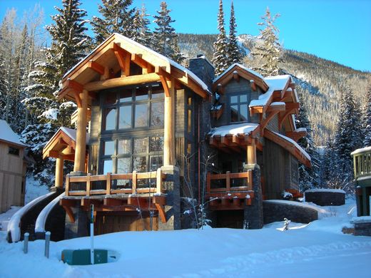 Snowy mountain chalet with large windows and wooden balconies in a pine forest
