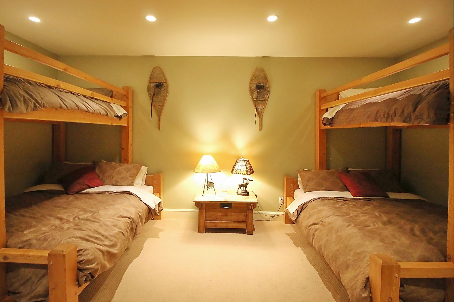 Cozy bedroom with two bunk beds, warm lighting, and a small table between them