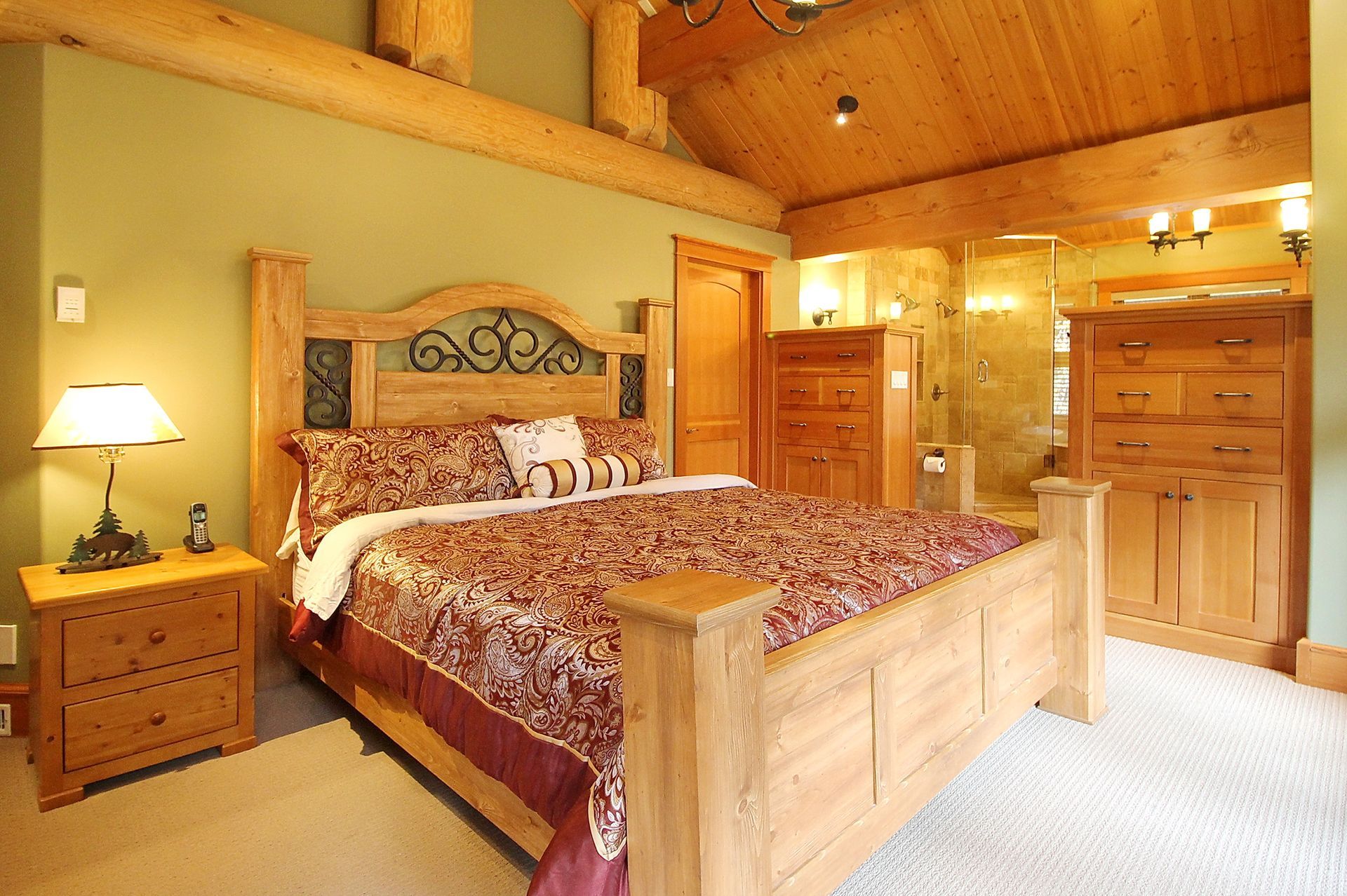 Cozy wooden bedroom with log bed, patterned bedding, dresser, and warm cabin lighting