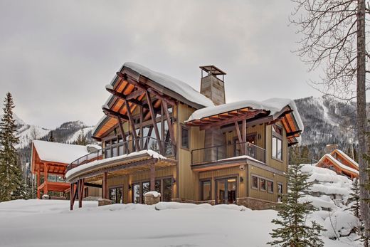 Snow-covered mountain lodge with warm-lit wooden balconies and steep roofs in a winter landscape