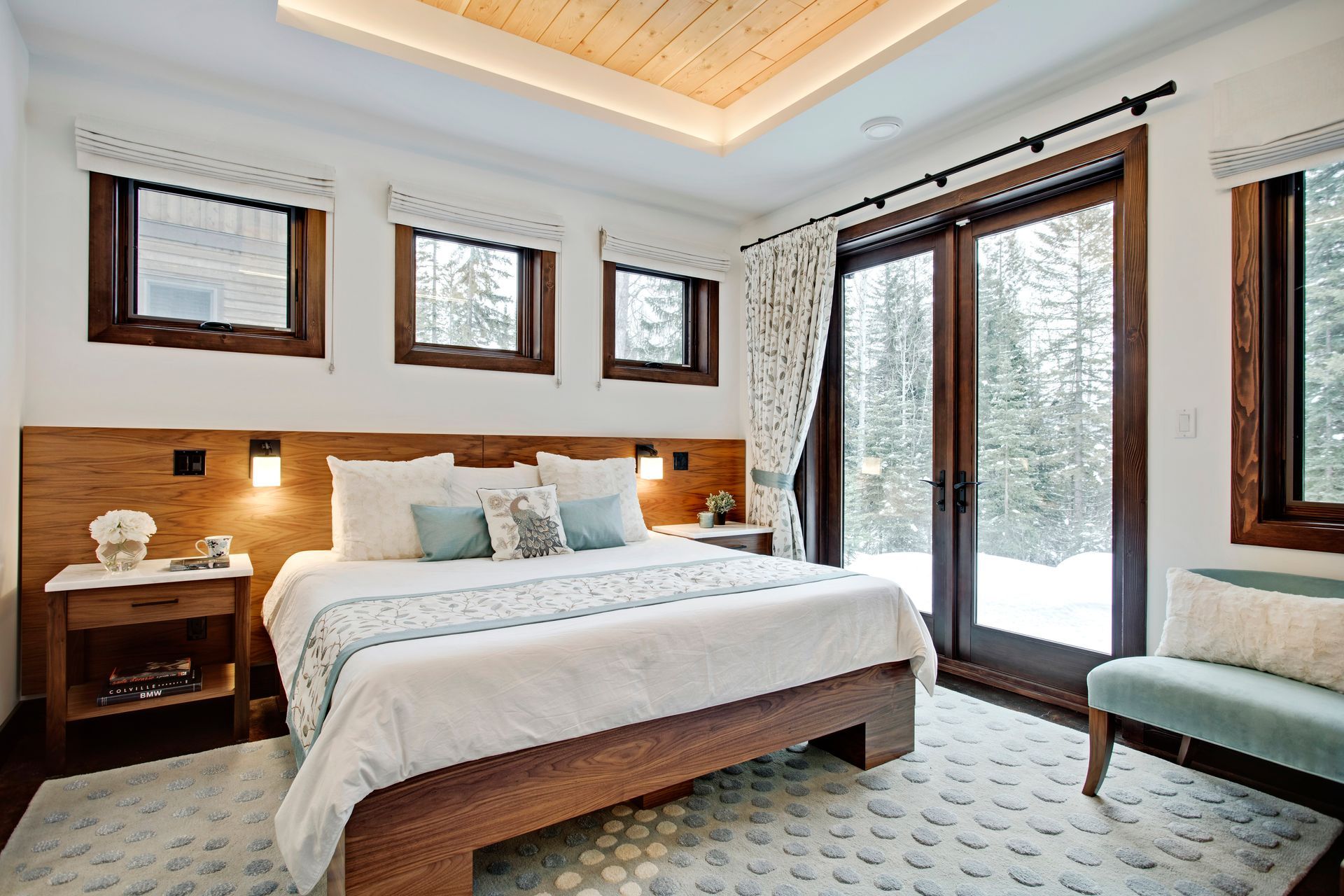 Bright bedroom with king bed, wooden nightstands, and sliding glass doors to a snowy view