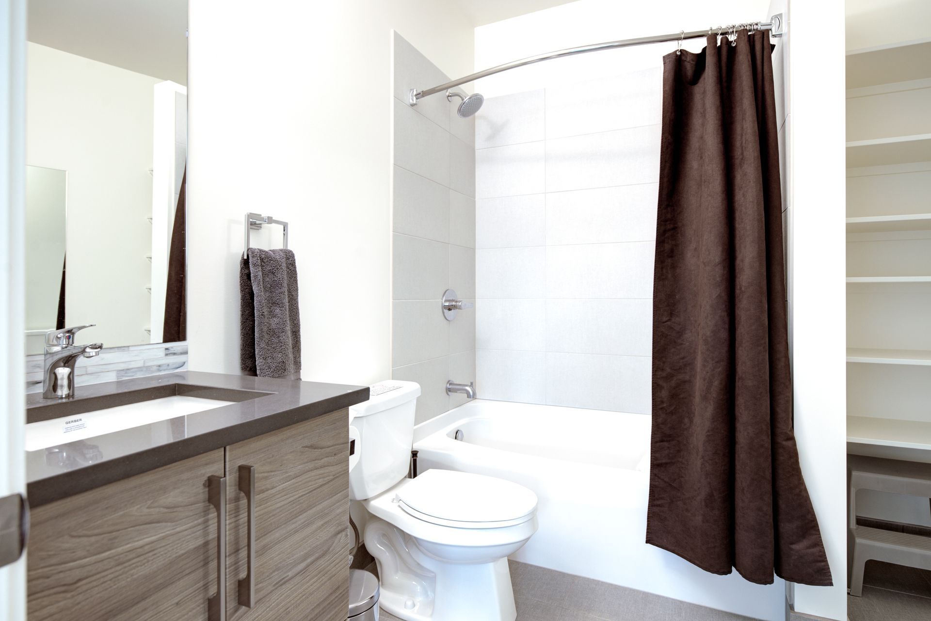 Bright modern bathroom with vanity, toilet, bathtub, and dark shower curtain