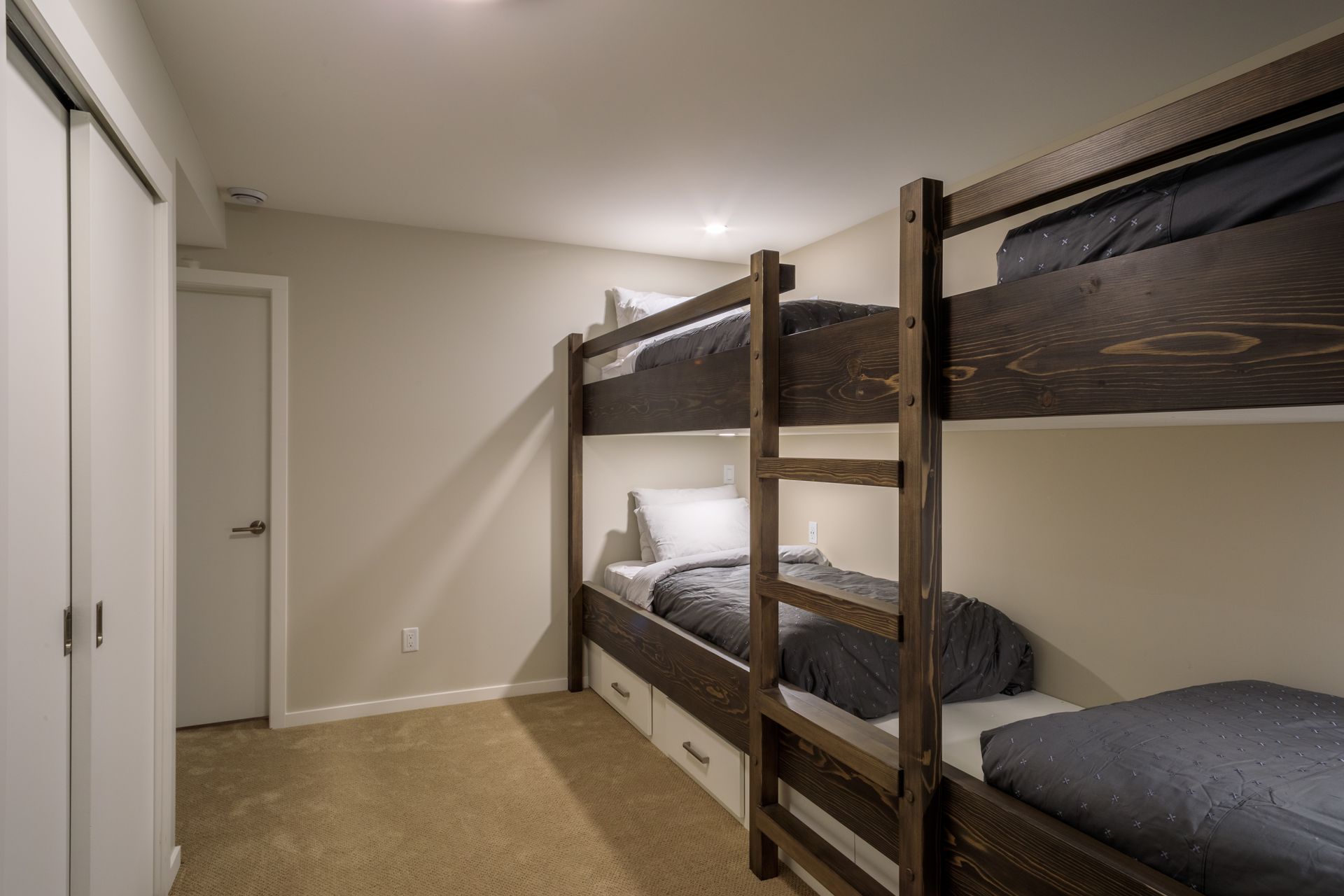 Bedroom with dark wood bunk beds, white walls, and beige carpet.