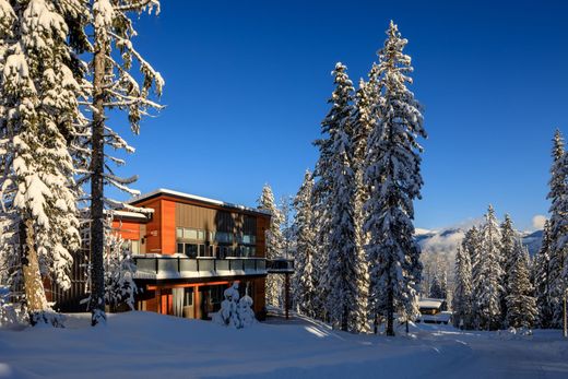 Snowy lodge with tall pine trees under a clear blue sky
