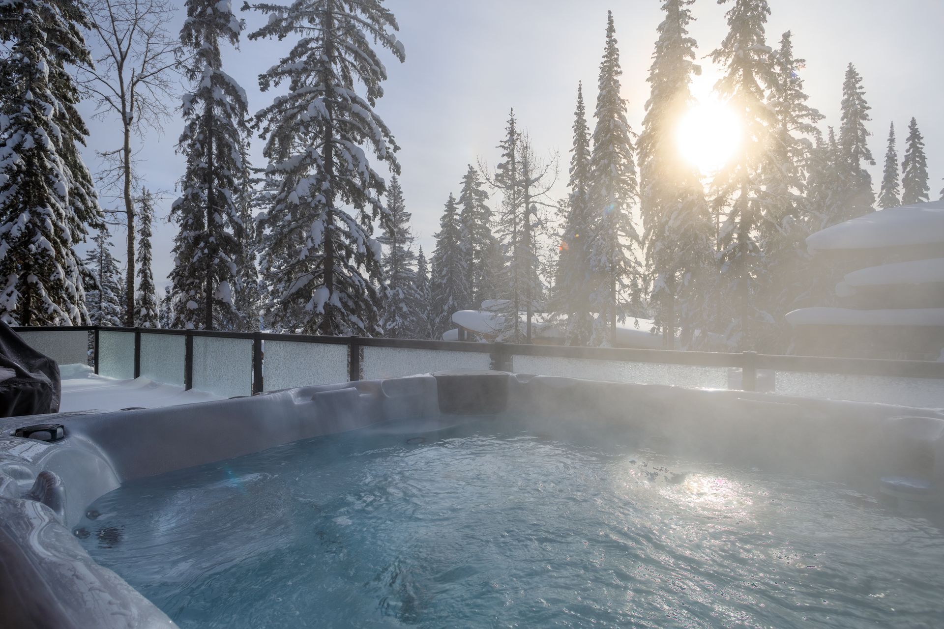 Steaming outdoor hot tub in a snowy pine forest at sunrise