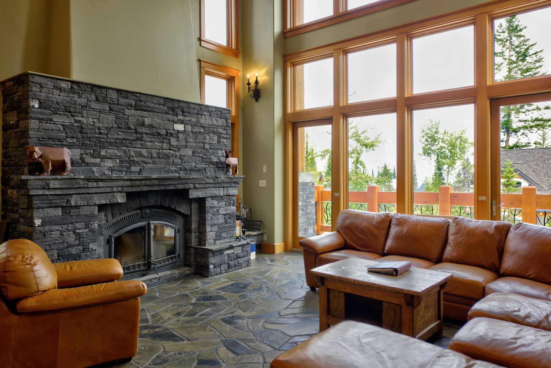Spacious living room with stone fireplace, leather sofas, wooden coffee table, and large windows