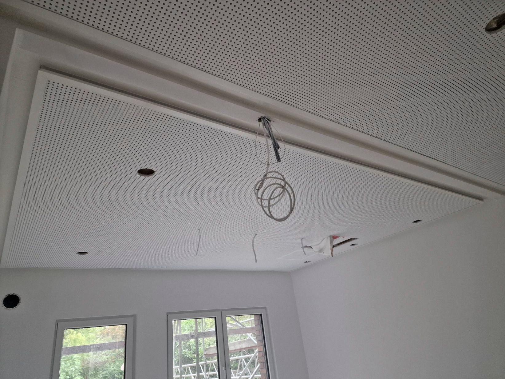Weiße Lochdecke mit Einbauleuchten und Verkabelung.