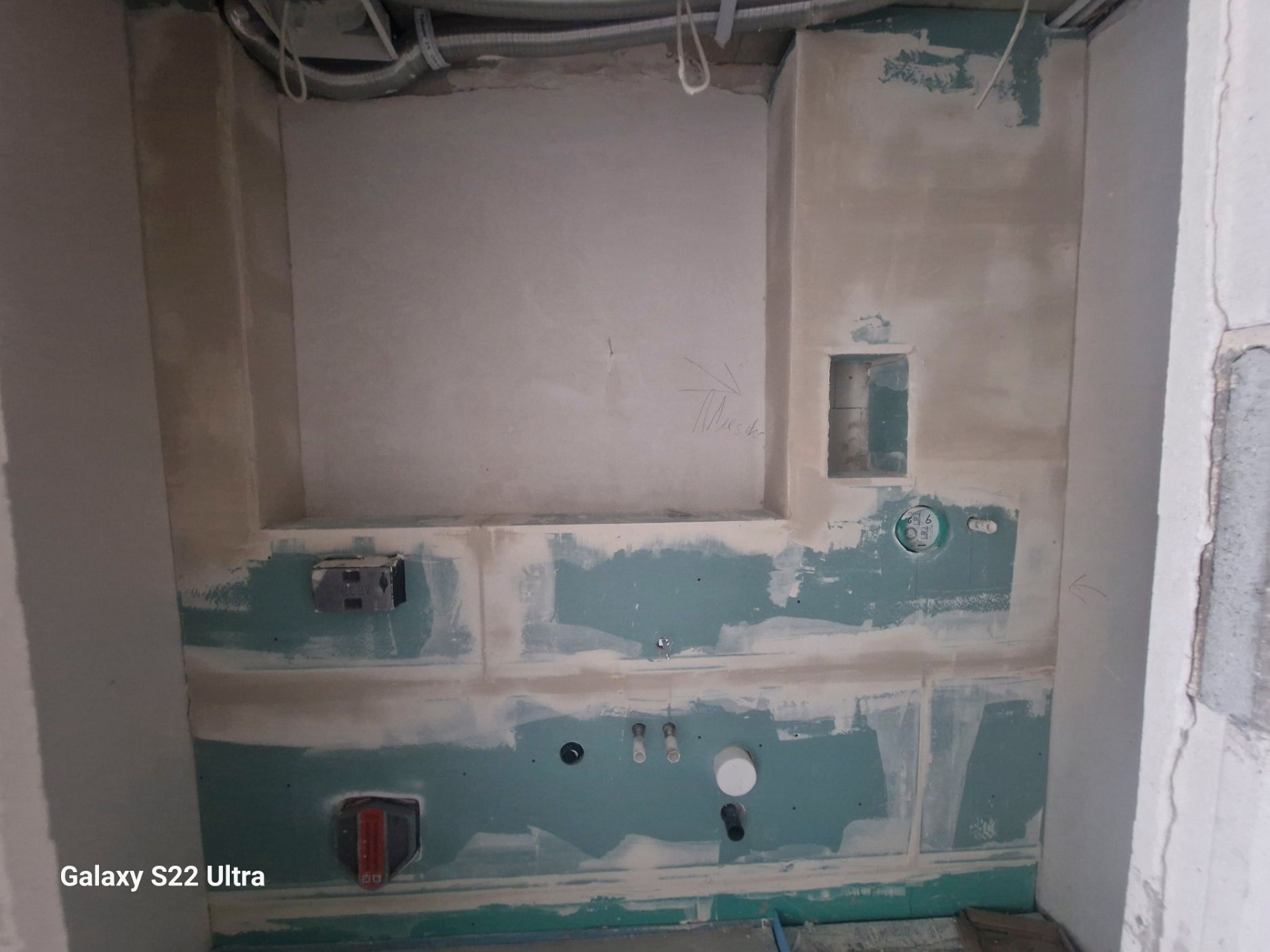 Innenraum eines im Bau befindlichen Badezimmers mit blauer Trockenbauwand, Steckdosen und Sanitärarmaturen.