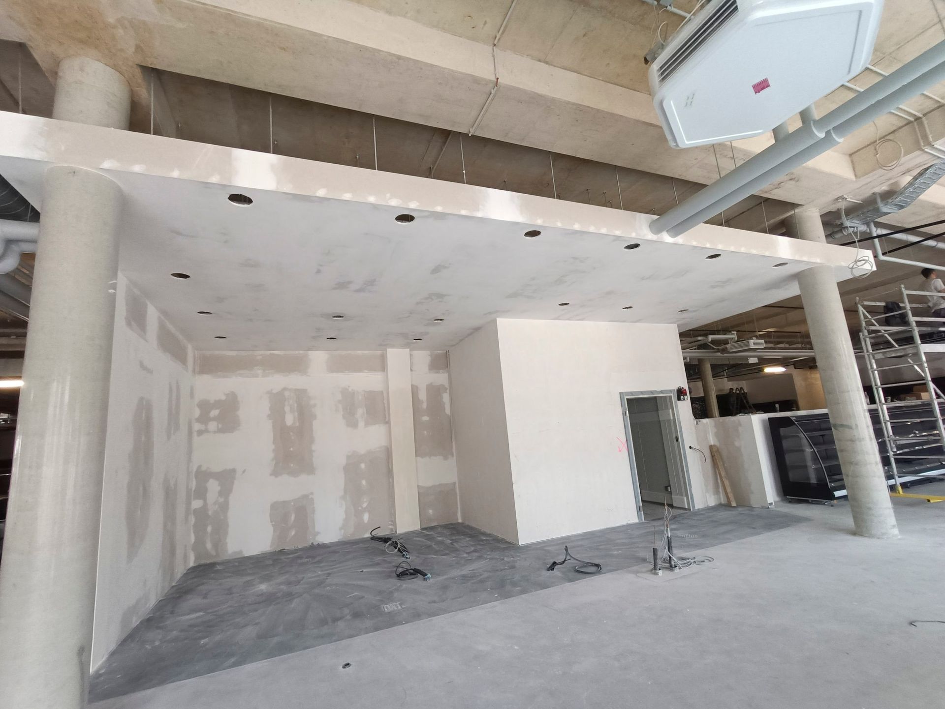 Innenausbau: Wände und Decken aus Trockenbau, Betonboden, zylindrische Säulen und freiliegende Infrastruktur.