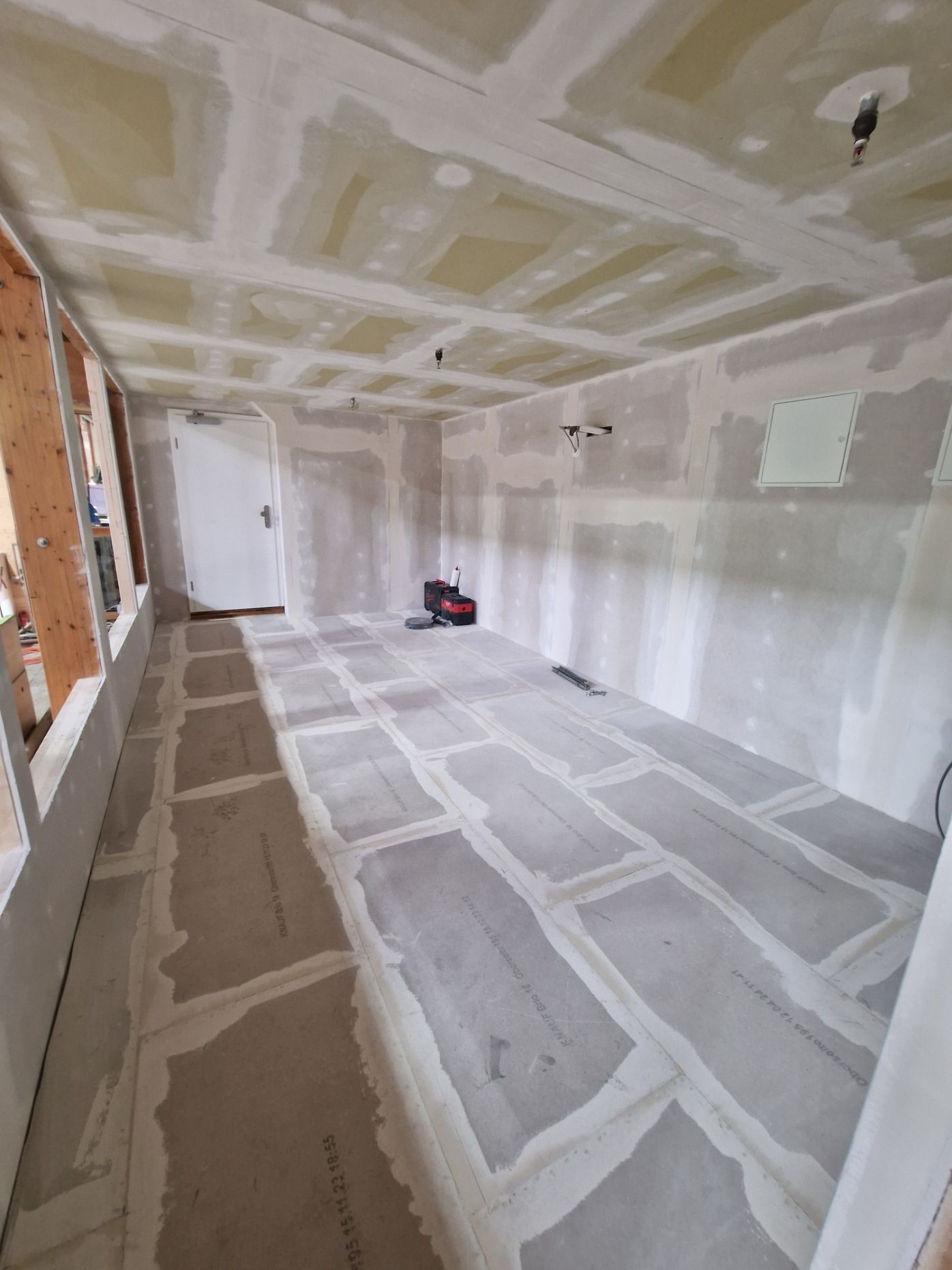 Raum im Bau mit Trockenbauwänden, Decke und Boden. Weiße Masse ist sichtbar.