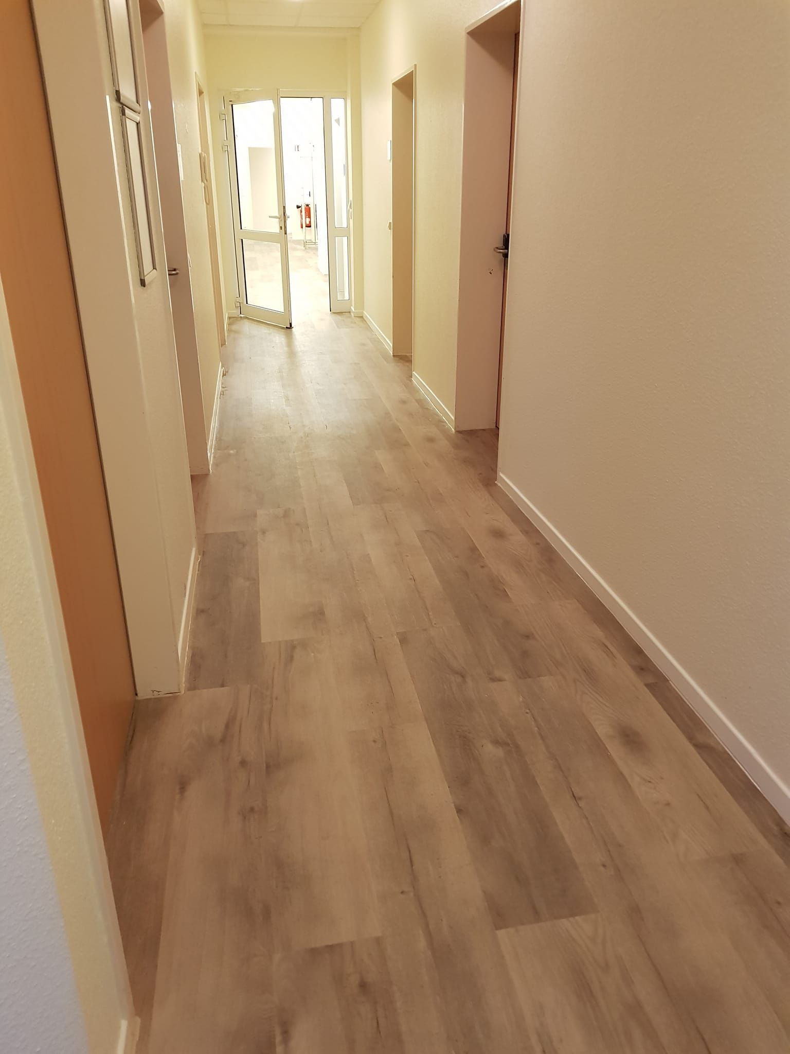 Ein langer Flur mit Holzboden und weißen Wänden.