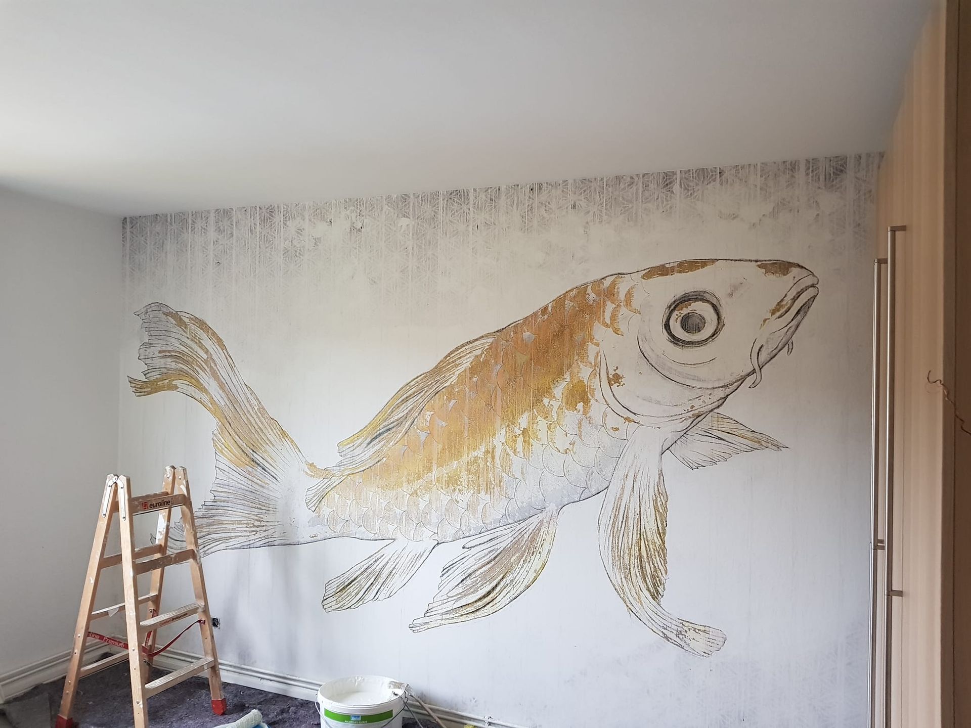 Ein Raum mit einer Leiter und einem Gemälde eines Fisches an der Wand.