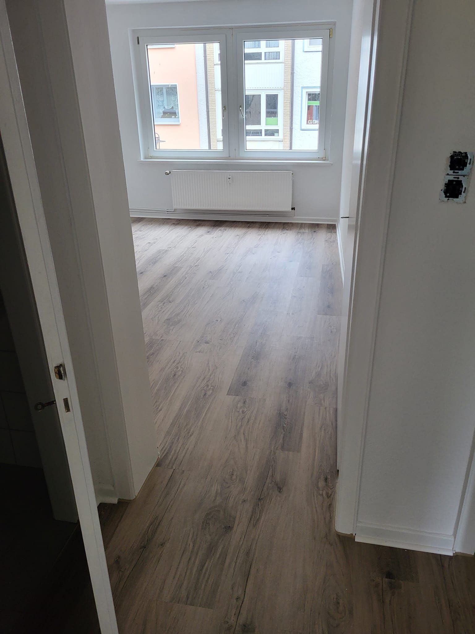 Ein leerer Raum mit Holzboden und Fenster.