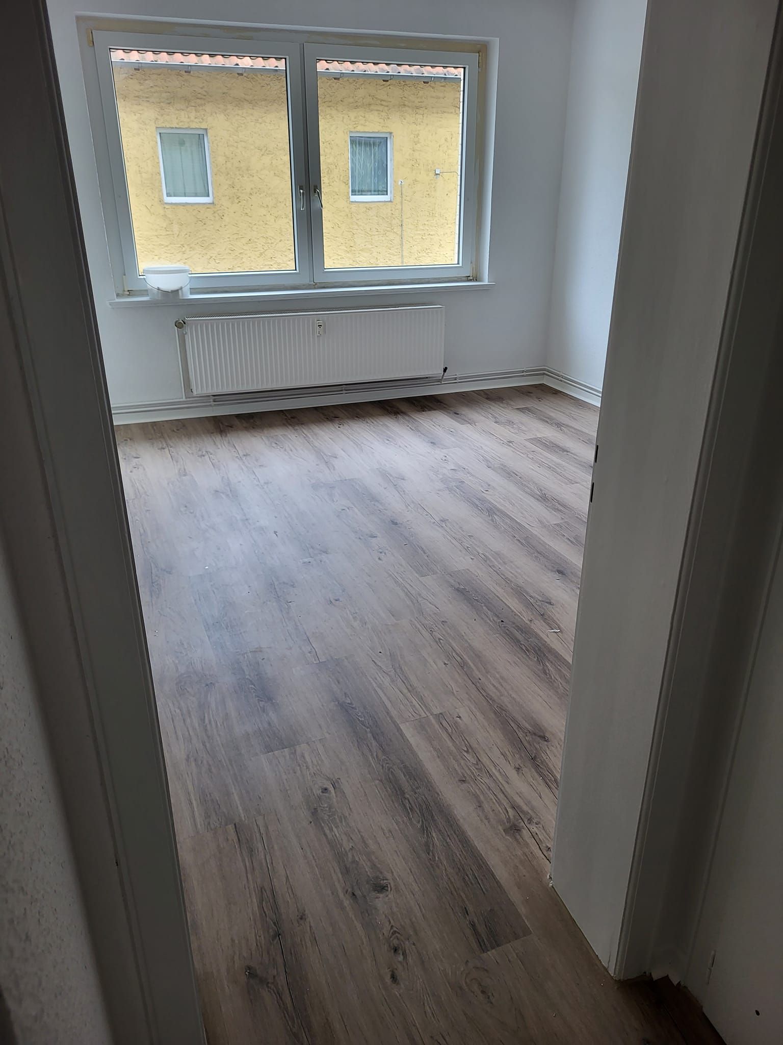 Ein leerer Raum mit Holzboden und Fenster.