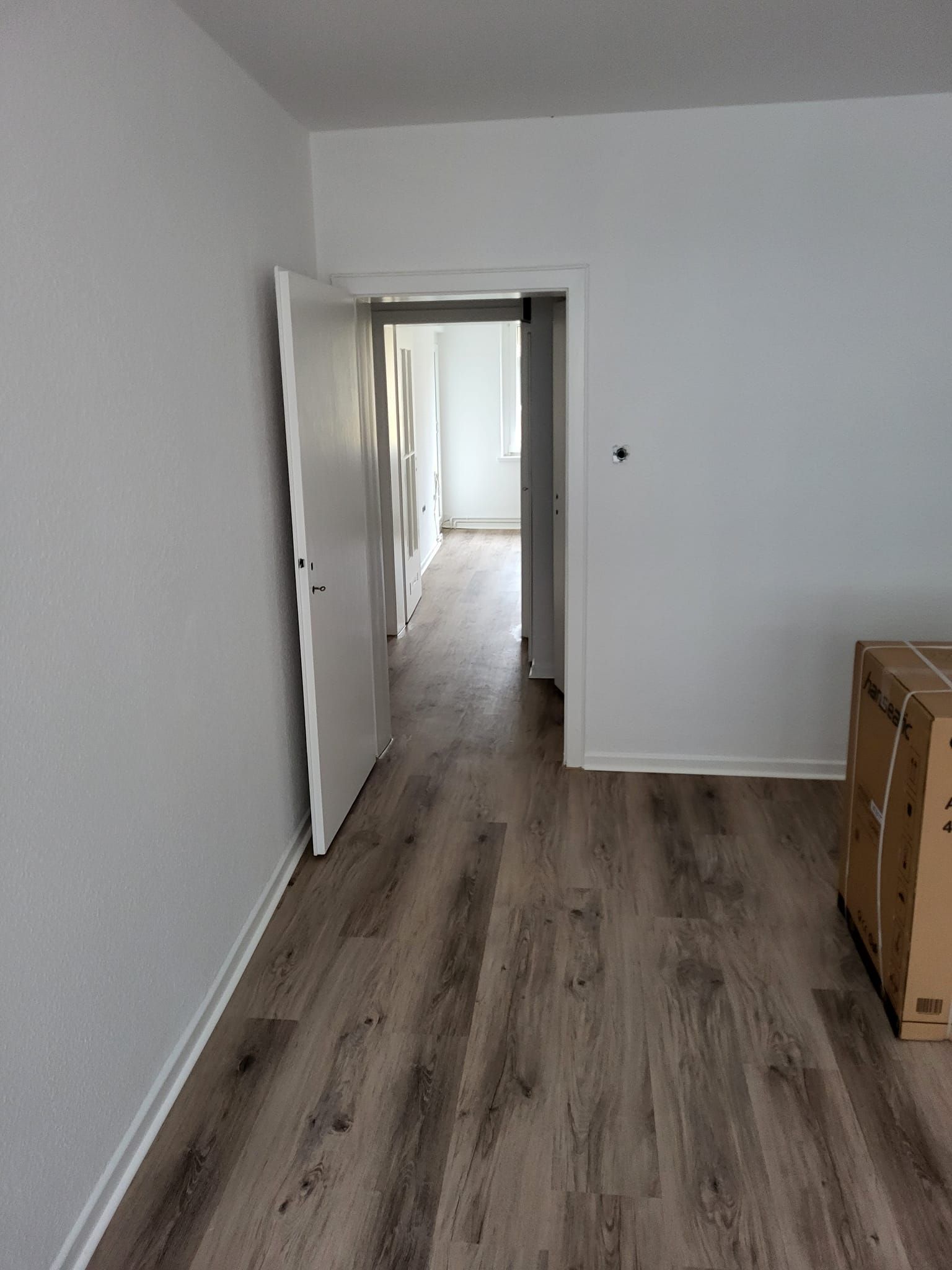Ein leerer Raum mit Hartholzböden und einem Karton auf dem Boden.