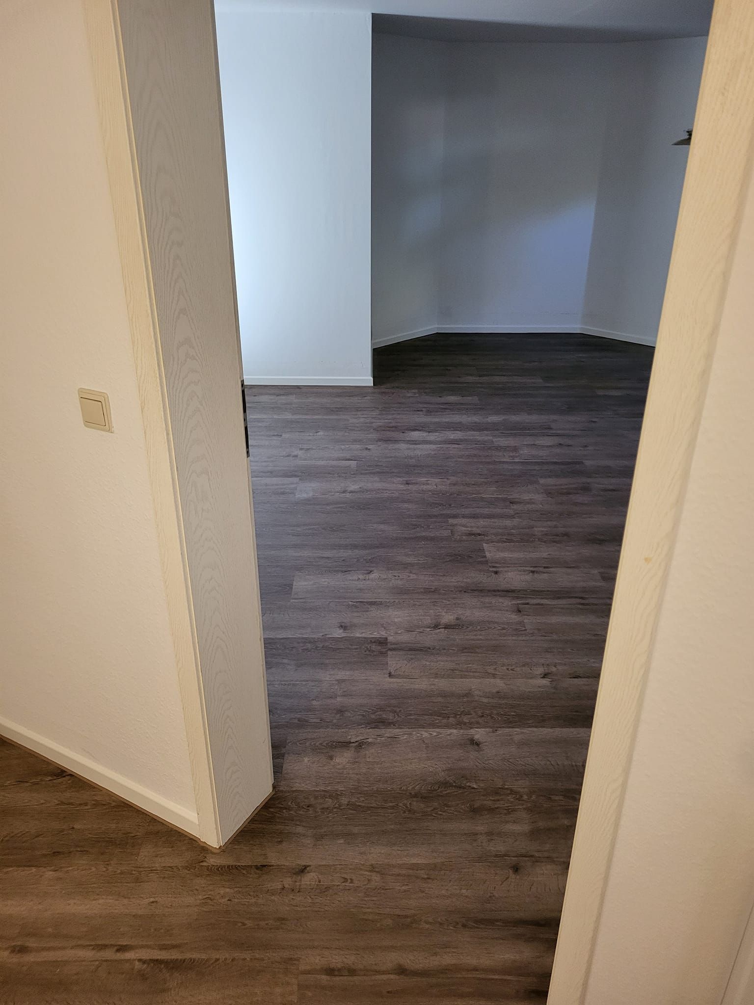 Ein Raum mit Holzboden und weißen Wänden.