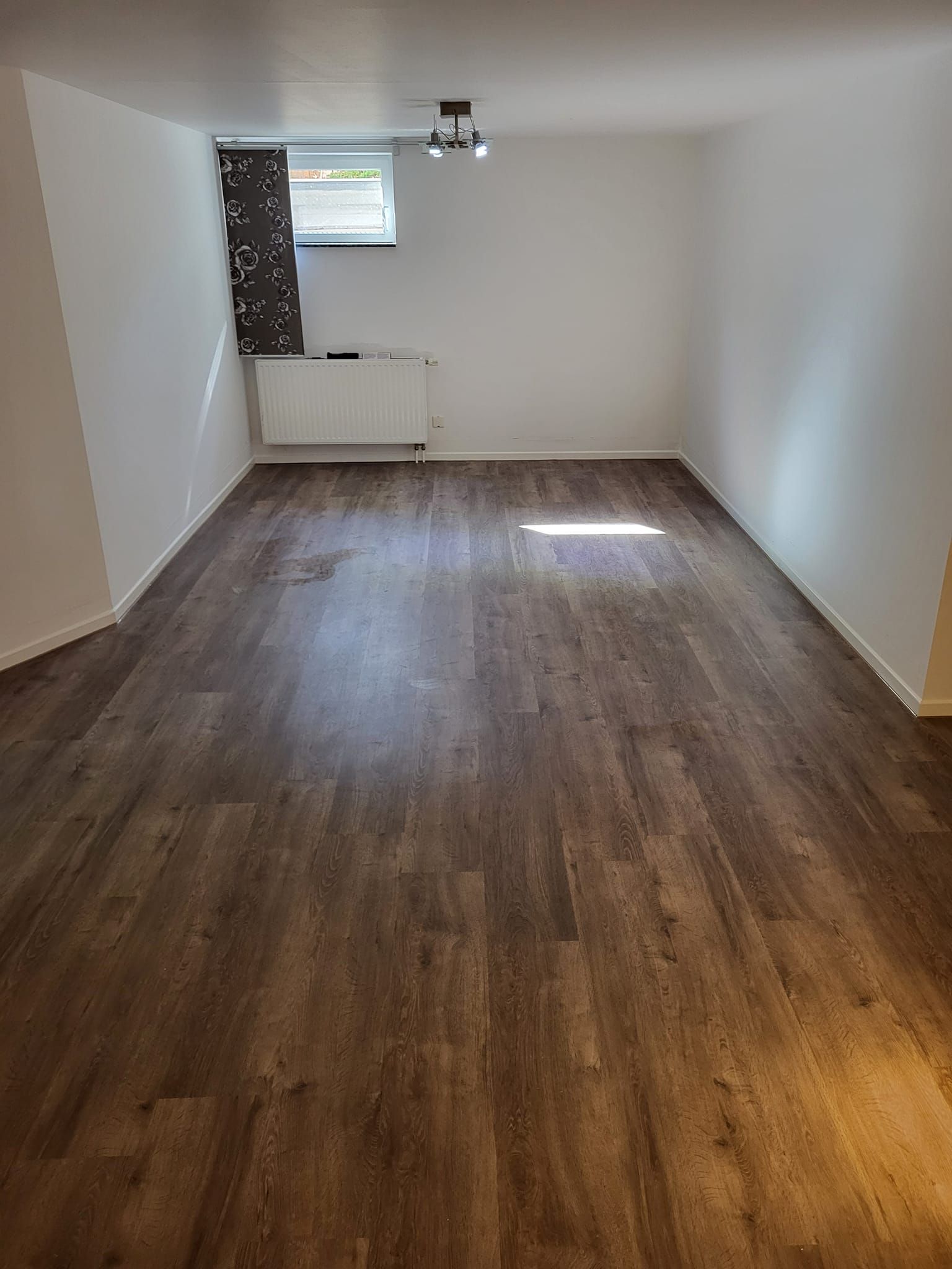 Ein Wohnzimmer mit Holzboden und weißen Wänden.