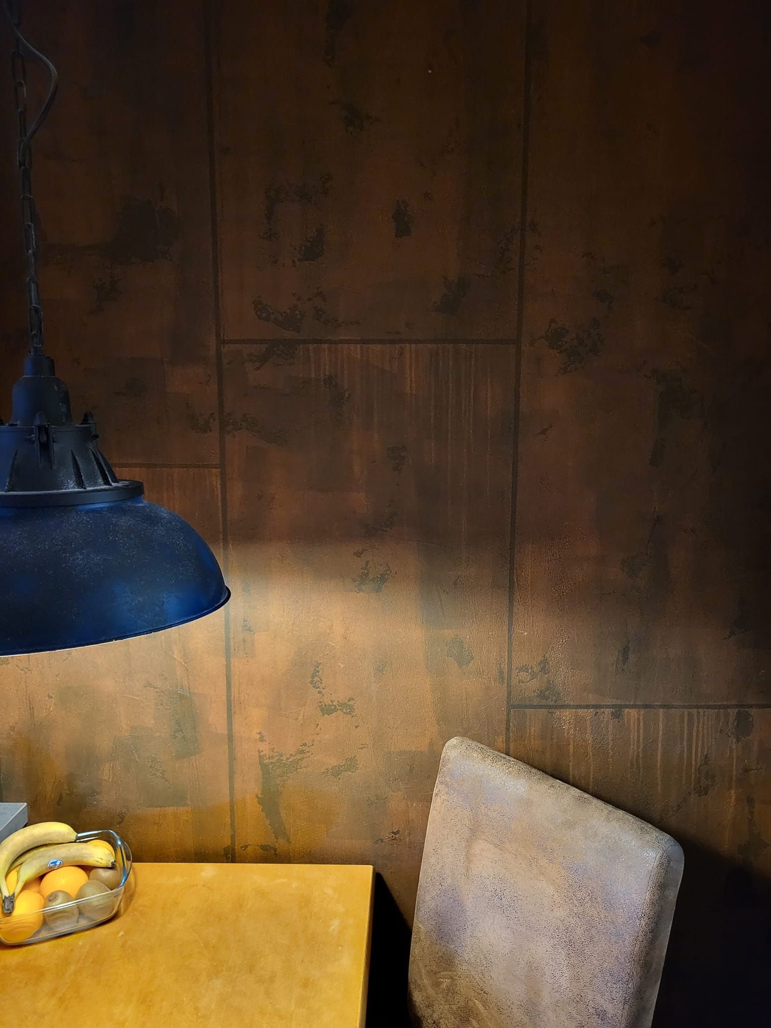 Ein Esstisch mit einer Schale mit Bananen und Orangen darauf.