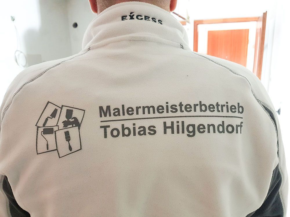 Auf der Rückseite einer Herrenjacke steht Malermeisterbetrieb Tobias Hilgendorf