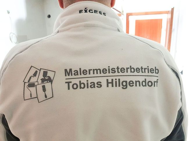 Auf der Rückseite einer Herrenjacke steht Malermeisterbetrieb Tobias Hilgendorf