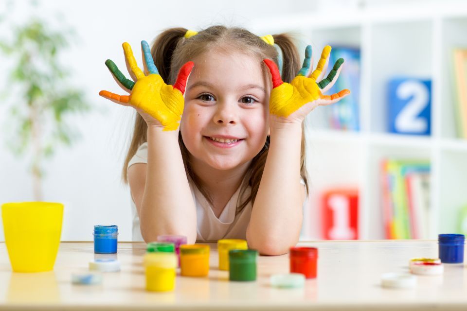 Ein Mädchen mit Fingermalfarbe an den Händen