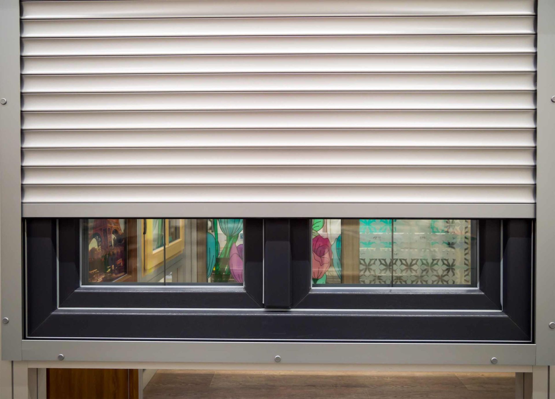 Una ventana con una persiana blanca y un marco negro.