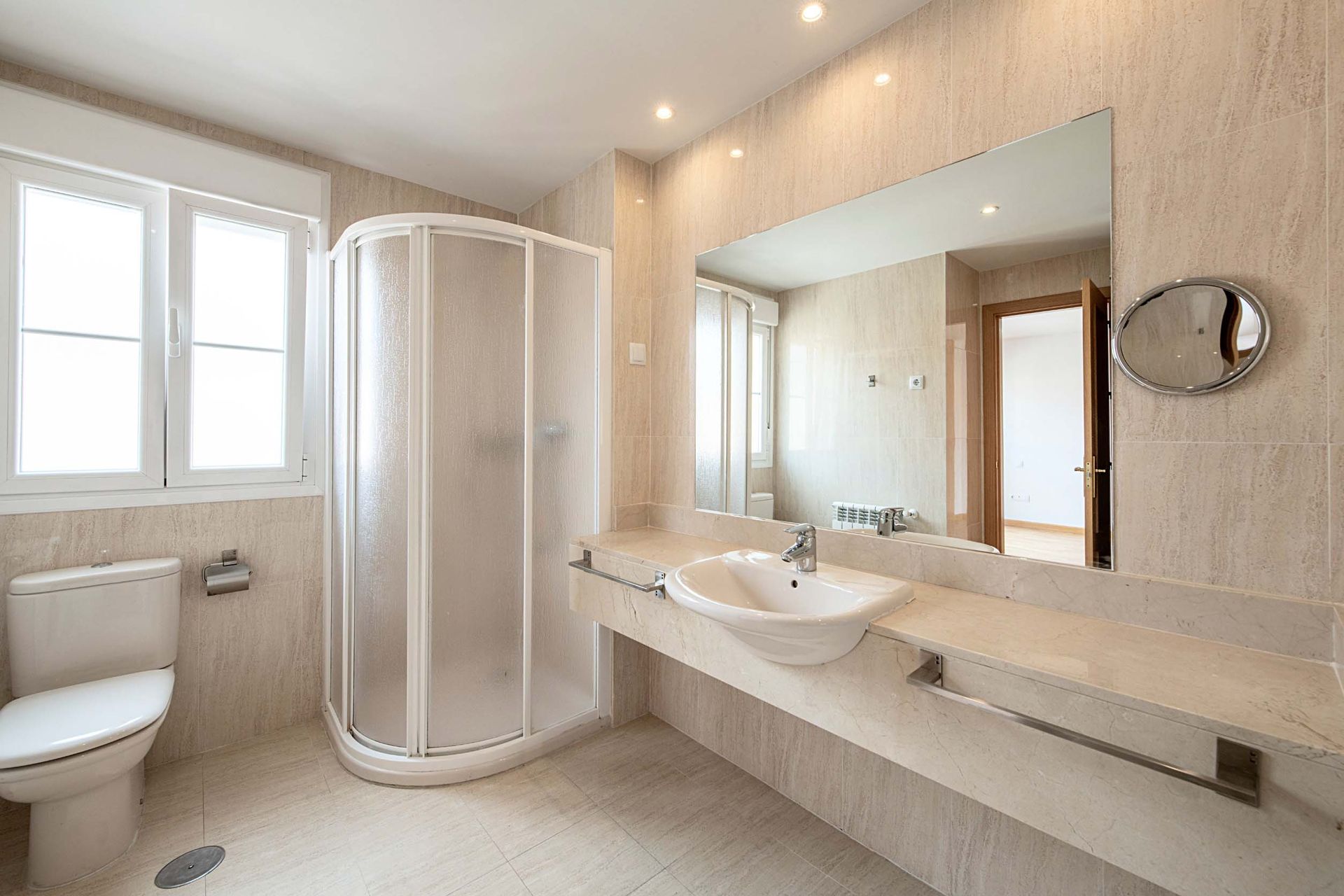 Un baño con inodoro, lavabo, ducha y espejo.
