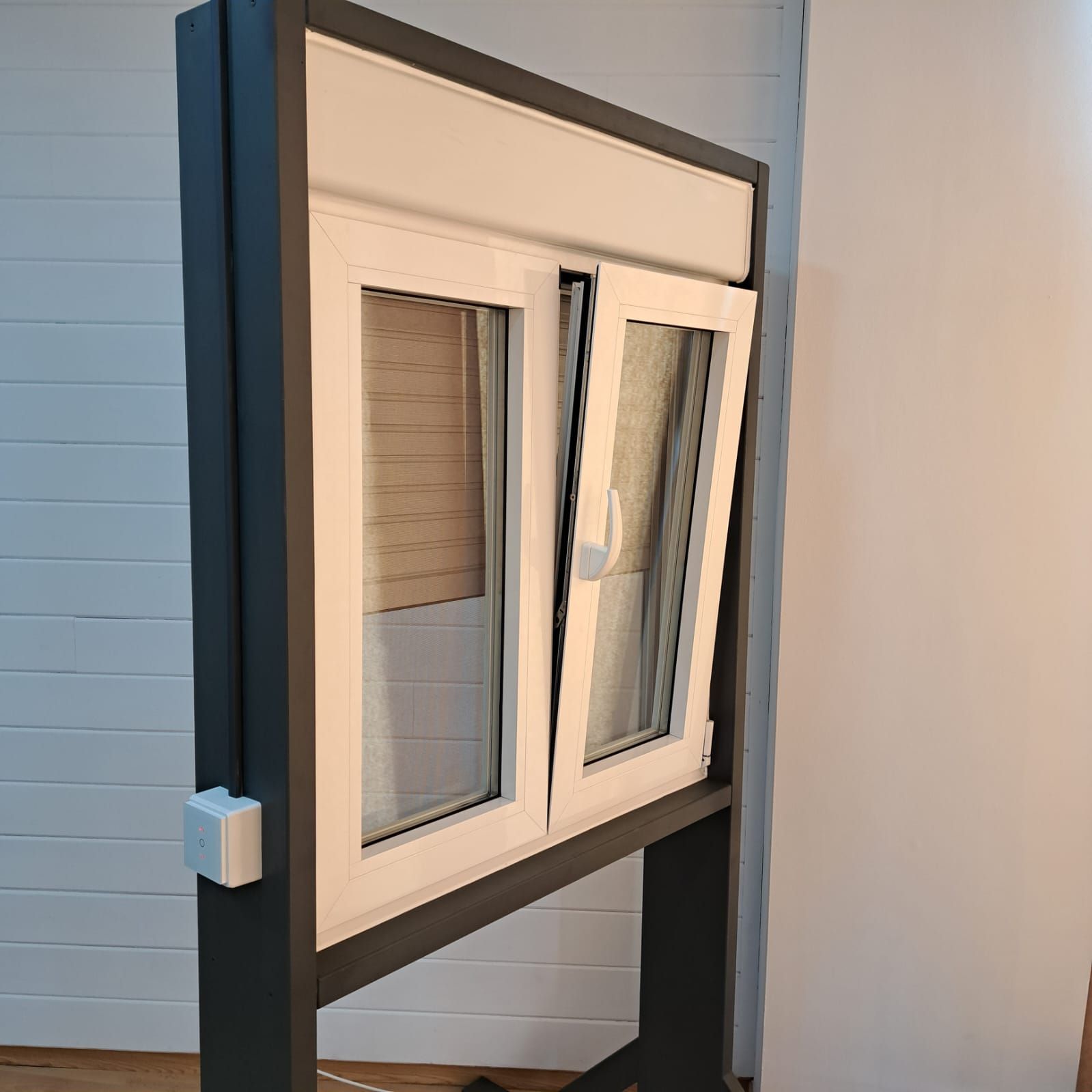 Una ventana blanca con un marco negro está colocada sobre un soporte.