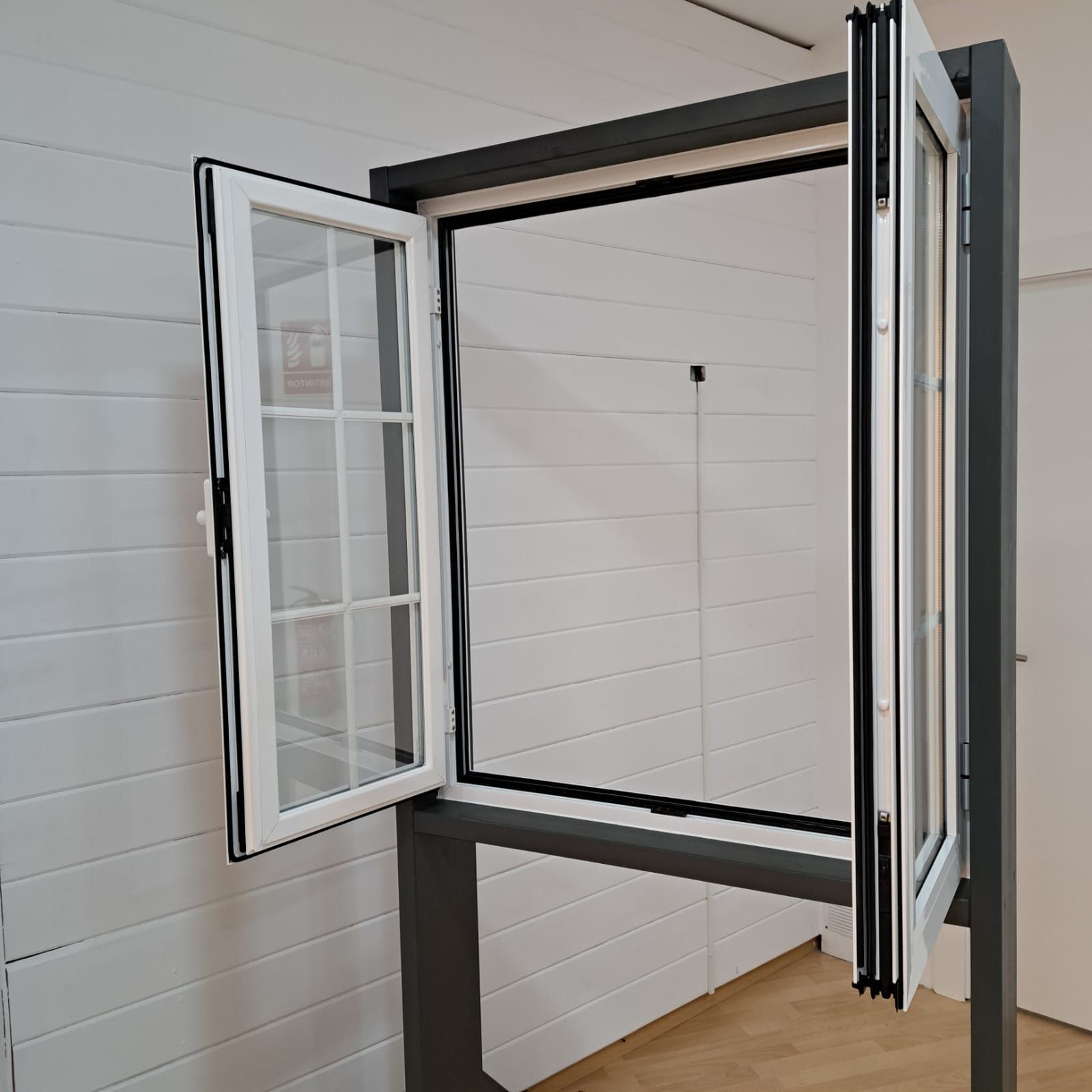 Una ventana blanca con un marco negro está abierta en una habitación.