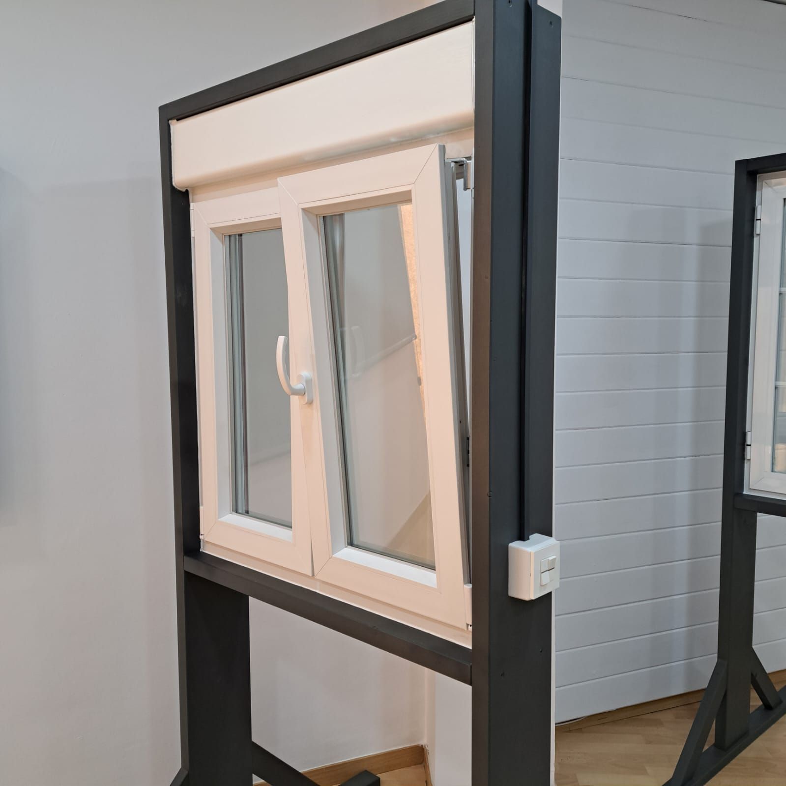 Una ventana blanca con un marco negro está expuesta en una habitación.