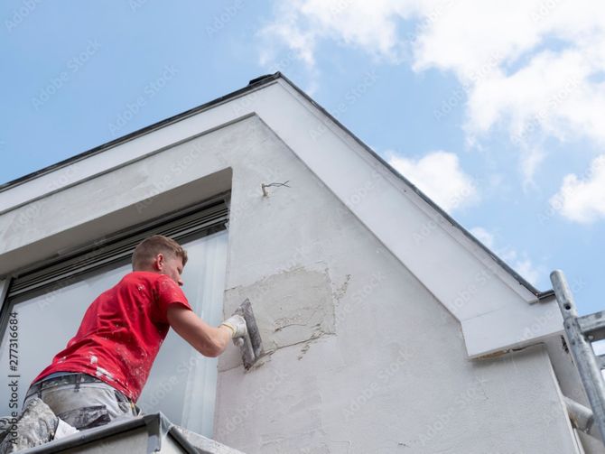 nna-bau GmbH - Mann in rotem Shirt auf Leiter beim Spachteln einer Hausfassade