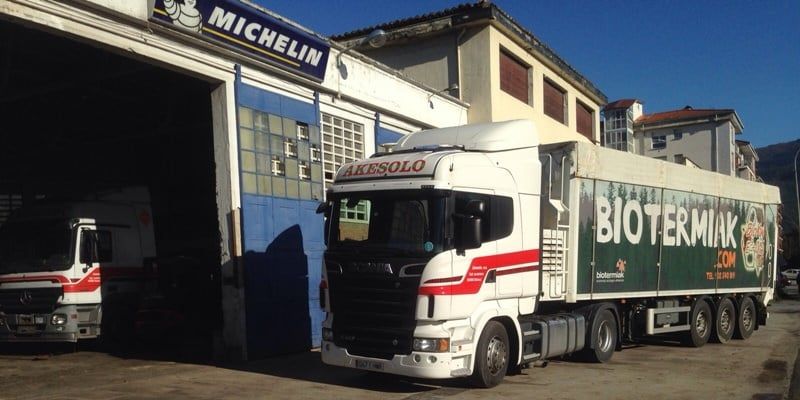 Dos camiones Michelin blancos aparcados frente a un edificio industrial, uno de ellos cargado con contenedores BioTermik.