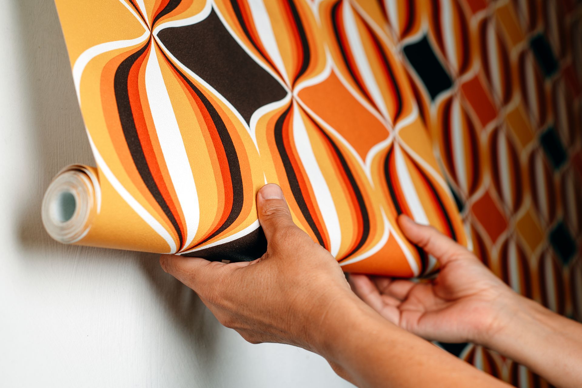 Personne en train de poser une tapisserie de couleur orange, blanche et noire