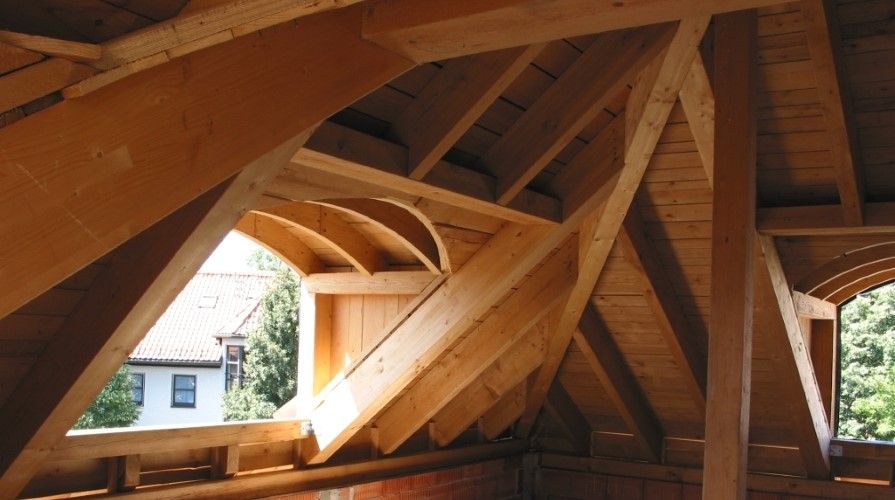 eine Person arbeitet an einem Holztisch mit der Sonne dahinter
