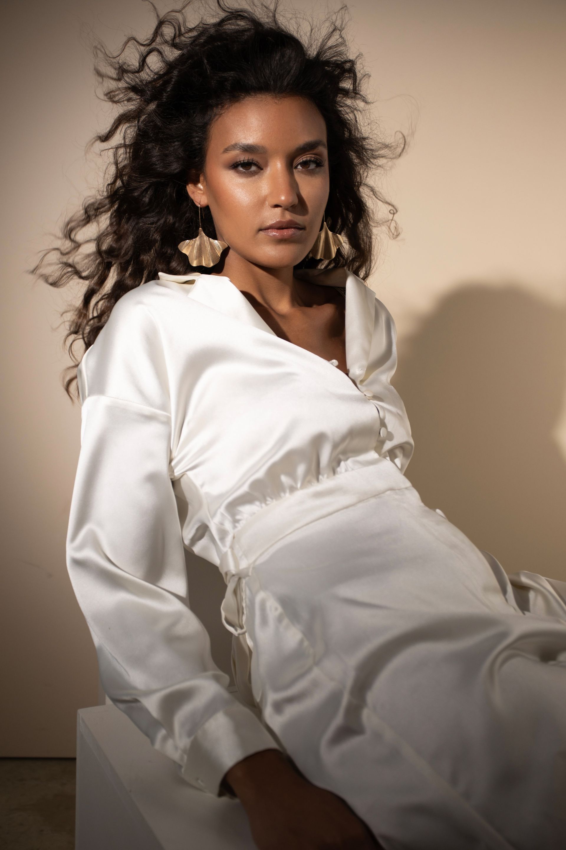 Eine Frau in einem weißen Kleid sitzt auf einem Würfel.